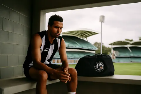 Grounded editorial scene illustrating Despite Bobby Hill’s absence and contract uncertainties, Collingwood coach Craig McRae affirms the star’s lasting welcome at the club as the team prepares for a key match against Adelaide.