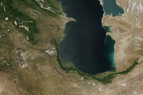 This is a view from orbit of the Caspian Sea as imaged by the MODIS sensor on the Terra satellite. Caption: The original caption from NASA : ::"The northern part of the Caspian Sea is plagued by a process called eutrophication , in which agricultural run-off rich in fertilizers stimulates rampant growth of algae in the water. The death and decay of these algae robs the water of oxygen, with obvious negative consequences for aquatic life. This image of the Caspian Sea shows swirls of green and blue near the mouth of the Volga River (top center), which indicate the presence of algae. The bright blue color of the northeastern part of the sea may be due to a mixture of plant life and sediment, for this is where the sea is most shallow. This image is from the Moderate Resolution Imaging Spectroradiometer (MODIS) on the Terra satellite on June 11 , 2003 .