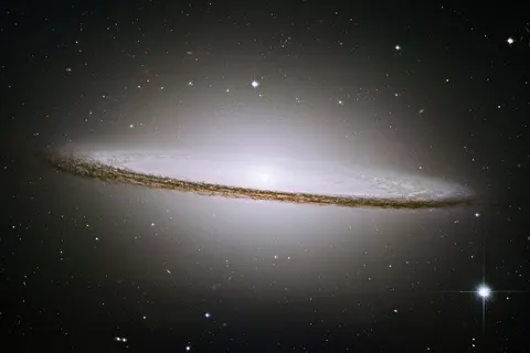 The famous Sombrero galaxy (M104) is a bright nearby elliptical galaxy. The prominent dust lane and halo of stars and globular clusters give this galaxy its name. Something very energetic is going on in the Sombrero's center, as much X-ray light has been detected from it. This X-ray emission coupled with unusually high central stellar velocities cause many astronomers to speculate that a black hole lies at the Sombrero's center - a black hole a billion times the mass of our Sun.
