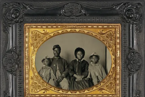 Photograph showing soldier in uniform, wife in dress and hat, and two daughters wearing matching coats and hats. In May 1863, U.S. Secretary of War Edwin Stanton issued General Order No. 143 creating the Bureau of U. S. Colored Troops. This image was found in Cecil County, Maryland, making it likely that this soldier belonged to one of the seven U.S.C.T. regiments raised in Maryland. (Source: Matthew R. Gross and Elizabeth T. Lewin, 2010) This is the only known photograph of an African American Union soldier with his family. Identified as Sgt. Samuel Smith of the 119th USCT, with his wife Mollie, and his daughters Mary and Maggie.