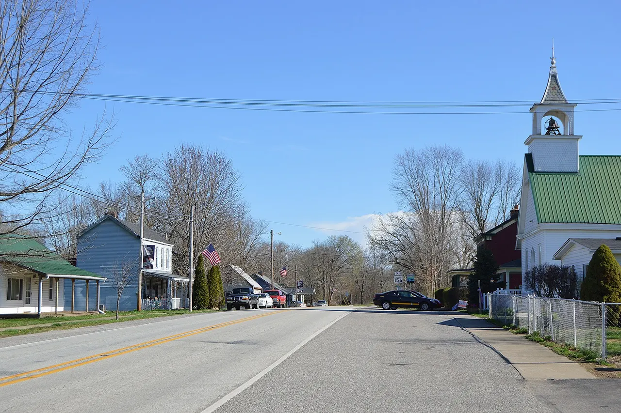Houses and a church on Main Street ( State Road 156 ), seen looking northeast from the Third Street intersection, in Patriot , Indiana , United States .