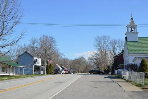 Houses and a church on Main Street ( State Road 156 ), seen looking northeast from the Third Street intersection, in Patriot , Indiana , United States .