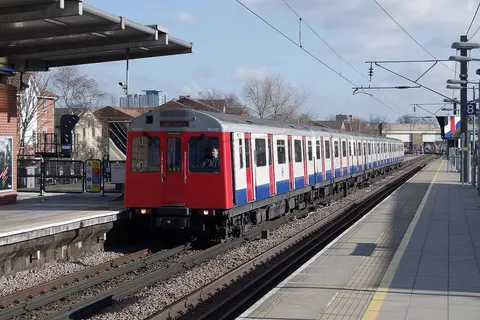 A London Underground District Line D Stock train arrives at West Ham with a westbound service.