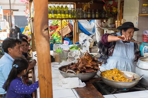 At the food market of Cajamarca, Peru, a family waits for its lunch to be served. This stand displays the local specialty: guinea pigs.