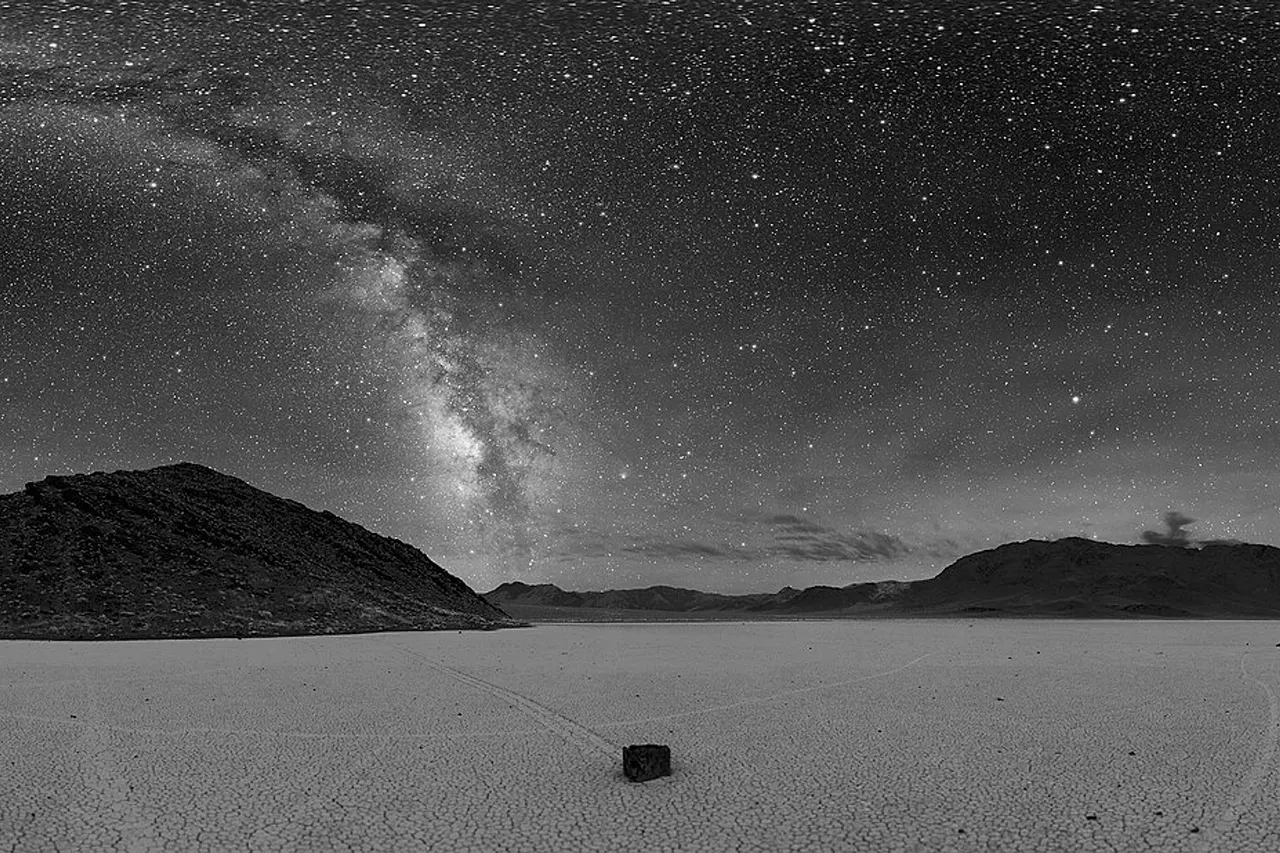 360° panorama of Racetrack Playa in Death Valley at night. The Milky Way is visible as the arc in the center. A sailing stone is also seen below along with the tracks of other stones.