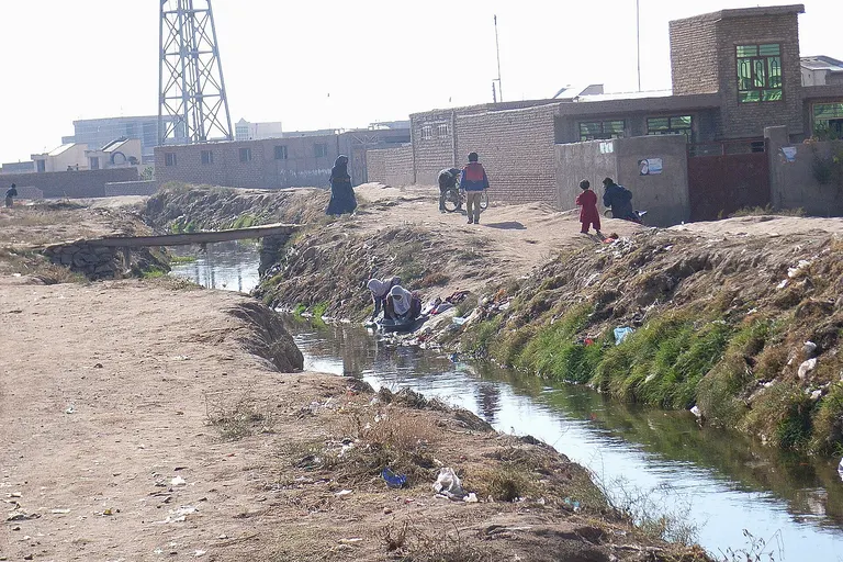 Drainage channel which also collects the greywater from the surrounding houses. A lady is washing clothes in the channel. (Photo: Nov. 2009, N. Khawaja, Herat)