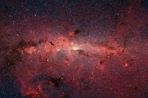 The center of our Milky Way galaxy is hidden from the prying eyes of optical telescopes by clouds of obscuring dust and gas. But in this stunning vista, the Spitzer Space Telescope's infrared cameras penetrate much of the dust, revealing the stars of the crowded galactic center region. The upcoming James Webb Space Telescope will offer a much-improved infrared view, teasing out fainter stars and sharper details. The center of our galaxy is a crowded place: A black hole weighing 4 million times as much as our Sun is surrounded by millions of stars whipping around it at breakneck speeds. This extreme environment is bathed in intense ultraviolet light and X-ray radiation. Yet much of this activity is hidden from our view, obscured by vast swaths of interstellar dust. NASA’s James Webb Space Telescope is designed to view the universe in infrared light, which is invisible to the human eye, but is very important for looking at astronomical objects hidden by dust. After its launch, Webb will gather infrared light that has penetrated the dusty veil, revealing the galactic center in unprecedented detail.