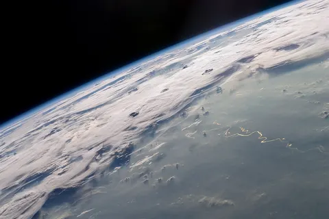 A picturesque line of thunderstorms and numerous circular cloud patterns filled the view as the International Space Station (ISS) Expedition 20 crew members looked out at the limb (blue line on the horizon) of the Earth . The region shown in the photograph includes an unstable, active atmosphere forming a large area of cumulonimbus clouds in various stages of development. The crew was looking west-south-west from the Amazon Basin , along the Rio Madeira toward Bolivia when the image was taken. The distinctive circular patterns of the clouds in the photograph are likely caused by the ageing of thunderstorms. Such ring structures often form during the final stages of storms development as their centres collapse. Sun-glint, the mirror-like reflection of sunlight off a water surface directly back to the camera on-board the ISS—is visible on the waters of the Rio Madeira and Lago Acara in the Amazon Basin. Widespread haze over the basin gives the reflected light an orange hue. The Rio Madeira flows northward and joins the Amazon River on its path to the Atlantic Ocean . A large smoke plume near the bottom centre of the image may be one source of the haze. The image was acquired with a Nikon D2Xs digital camera using an effective 48mm lens (28-70 mm zoom lens), and is provided by the ISS Crew Earth Observations experiment and Image Science & Analysis Laboratory, Johnson Space Centre.