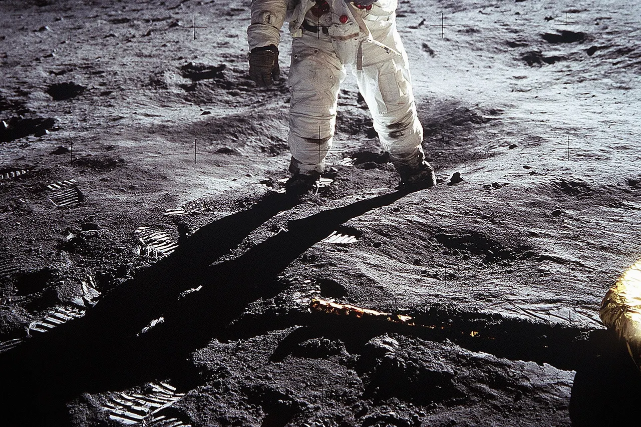 Short description : Astronaut Buzz Aldrin on the Moon Full description : Astronaut Buzz Aldrin , Lunar Module pilot, walks on the surface of the Moon near the leg of the Lunar Module (LM) "Eagle" during the Apollo 11 extravehicular activity (EVA). Astronaut Neil A. Armstrong , commander, took this photograph with a 70mm lunar surface camera. While astronauts Armstrong and Aldrin descended in the Lunar Module (LM) "Eagle" to explore the Sea of Tranquility region of the Moon, astronaut Michael Collins, command module pilot, remained with the Command and Service Modules (CSM) "Columbia" in lunar orbit. Variations : The upper black band is an addition to the original photo, carried out for "reasons of balance". See the original photo and the explanation of the edit at NASA's website . In the expanded version of the photo, it is possible to see a horizontal white line at the top left (viewer's right) of the helmet. This is the base of the antenna that was cut in the original frame of the photo.