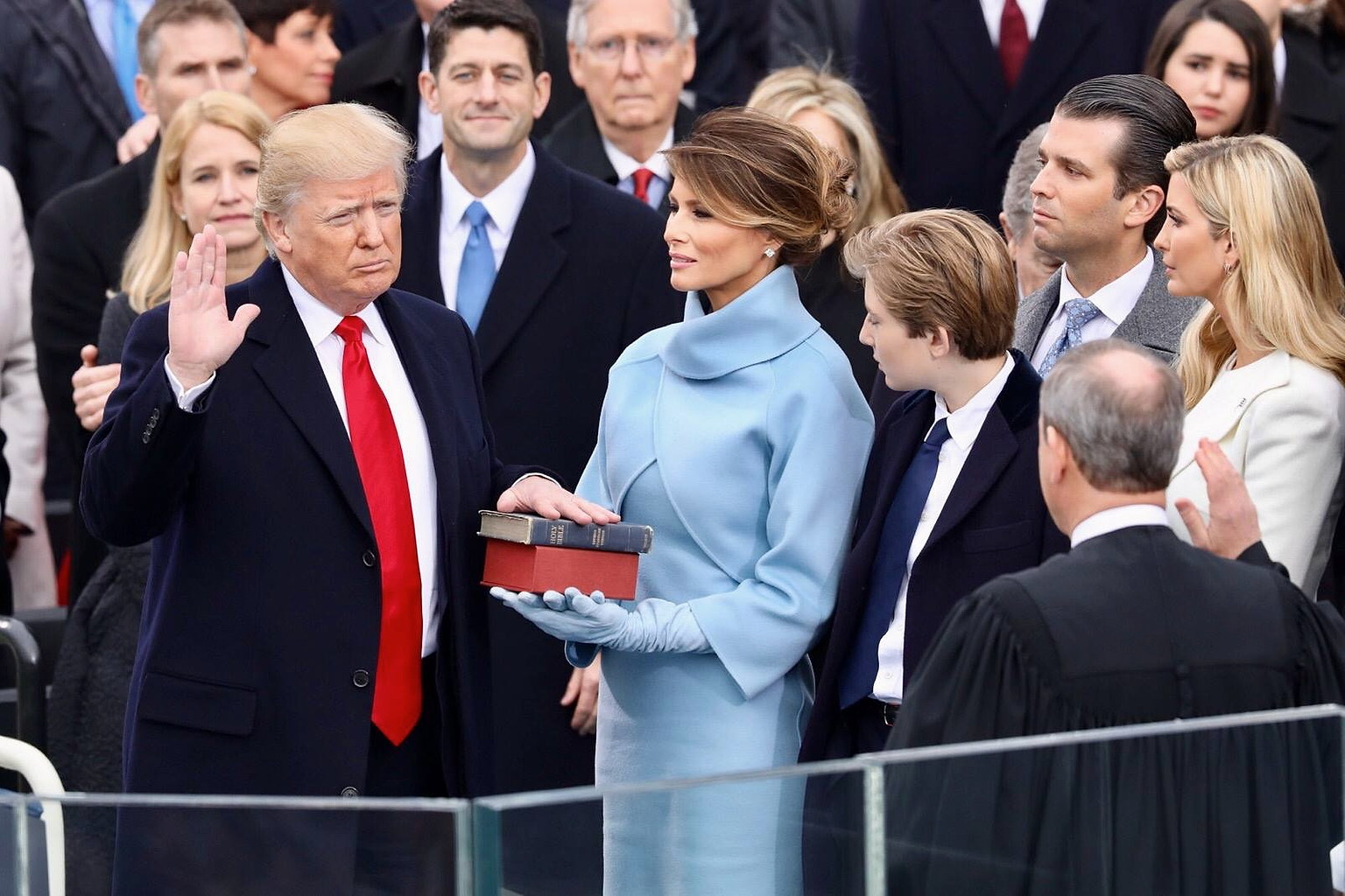 President Donald Trump being sworn in on January 20, 2017 at the U.S. Capitol building in Washington, D.C. Melania Trump wears a sky-blue cashmere Ralph Lauren ensemble. He holds his left hand on two versions of the Bible , one childhood Bible given to him by his mother, along with Abraham Lincoln’s Bible.