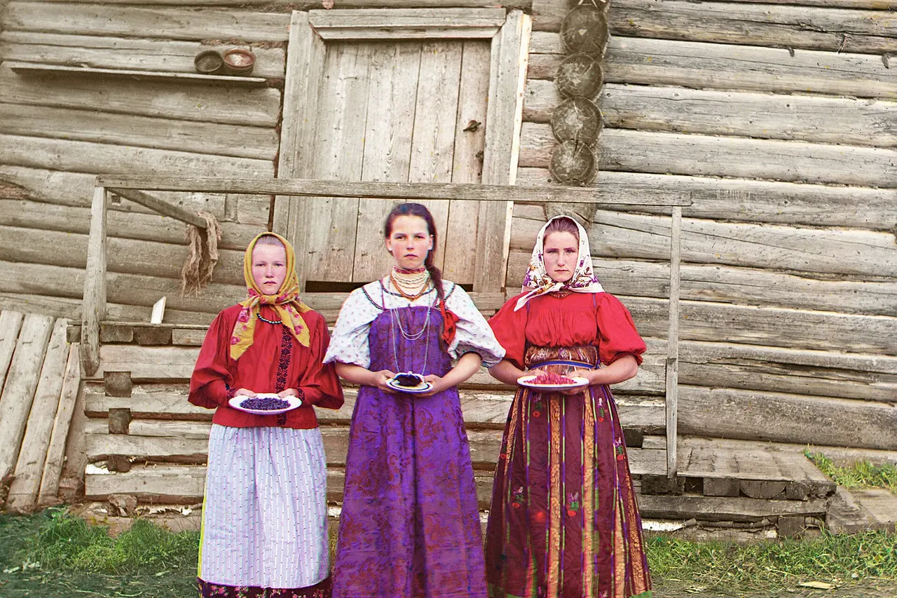 Young Russian peasant women in front of traditional wooden house, in a rural area along the Sheksna River near the small town of Kirillov . Early color photograph from Russia, created by Sergei Mikhailovich Prokudin-Gorskii as part of his work to document the Russian Empire from 1909 to 1915.